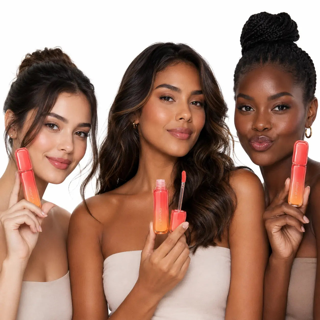 Três mulheres brasileiras de diferentes tons de pele segurando o gloss labial O Sfumato Coral Pêssego em fundo branco