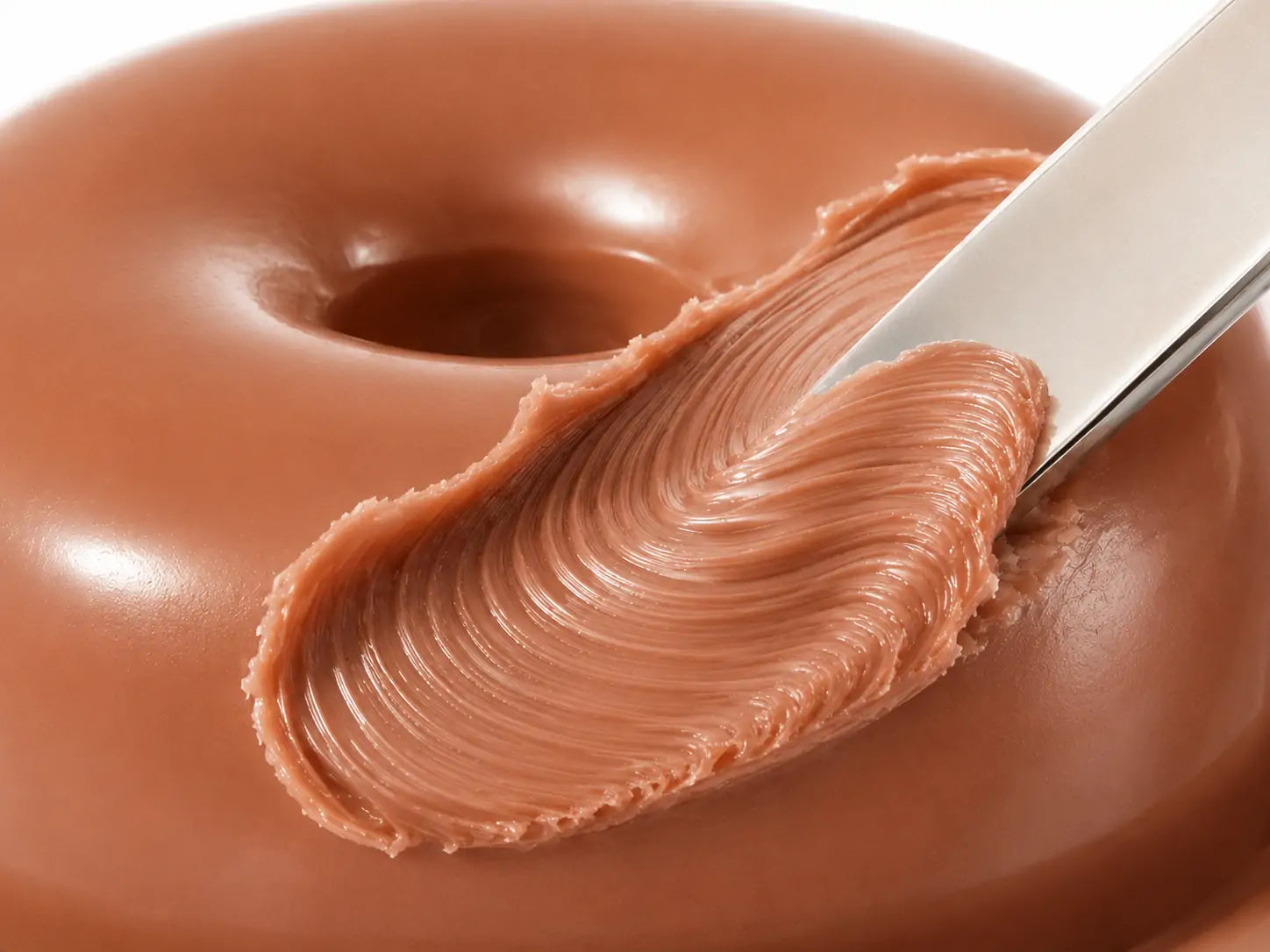 Close da textura cremosa do blush O Sfumato™ Caramel Nude Brown sendo retirado com espátula, mostrando o tom marrom caramelo nude.