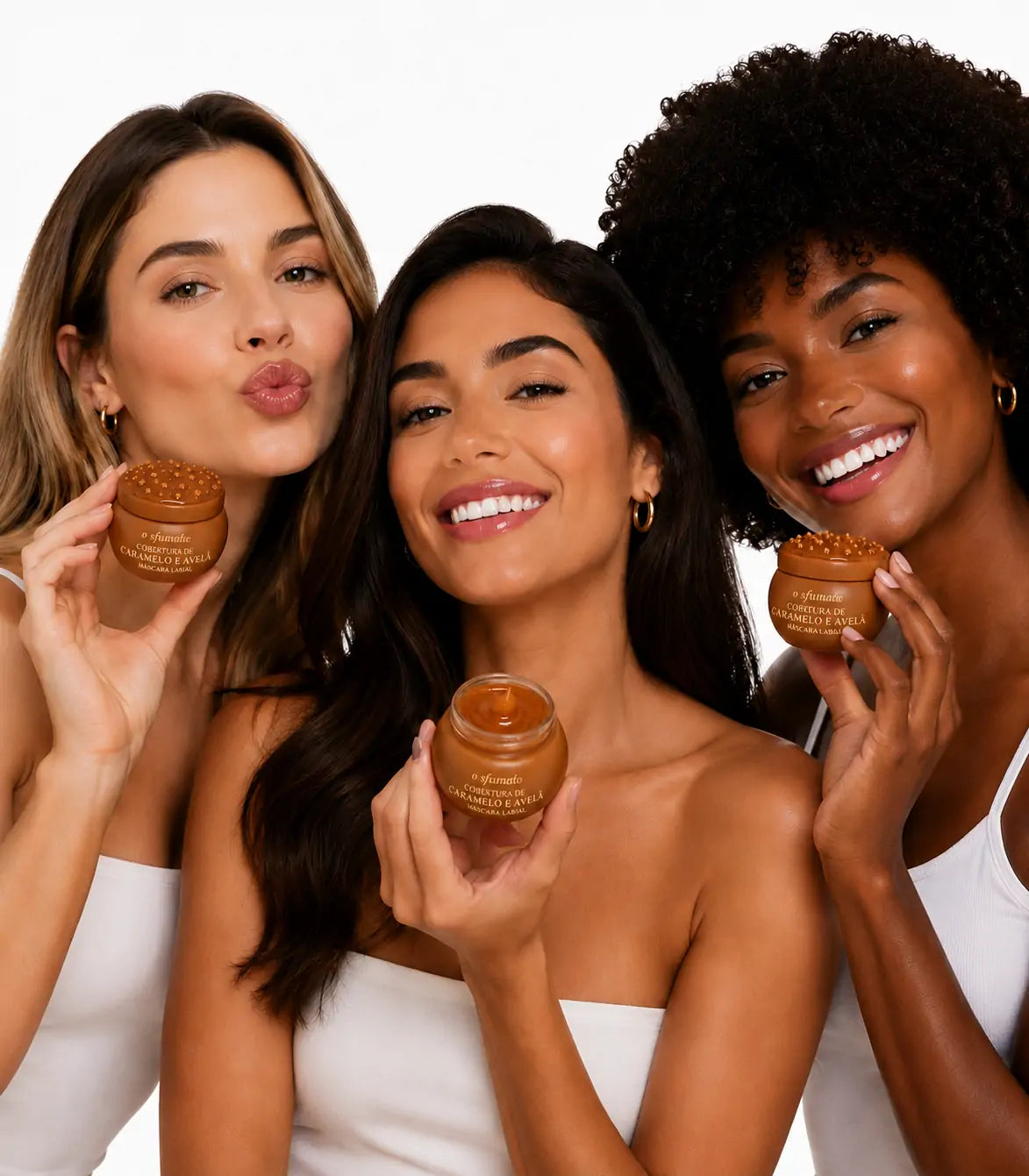 Três mulheres de diferentes tons de pele segurando a Máscara Labial O Sfumato™ Cobertura de Caramelo e Avelã em fundo branco.