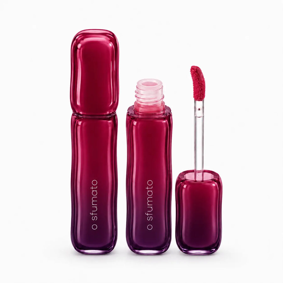 Gloss labial O Sfumato Amora Silvestre com embalagem em degradê roxo e rosa, frasco aberto e aplicador em fundo branco