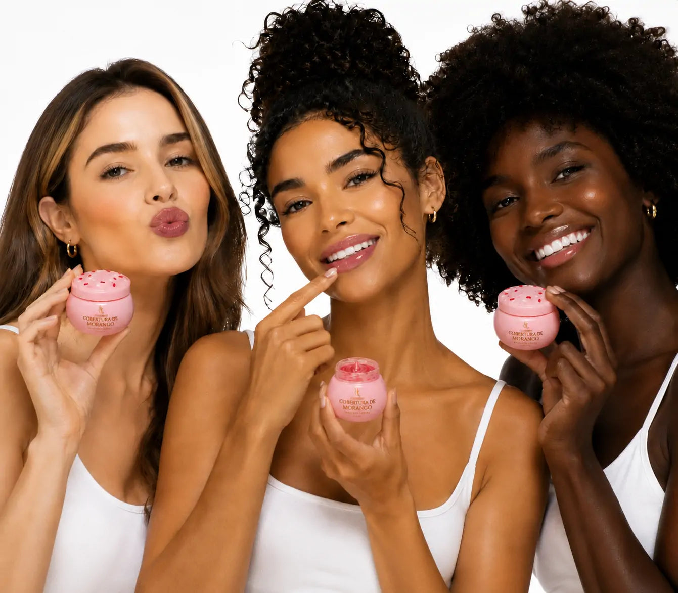 Três modelos com diferentes tons de pele usando e segurando a Máscara Labial O Sfumato™ Cobertura de Morango em fundo branco.