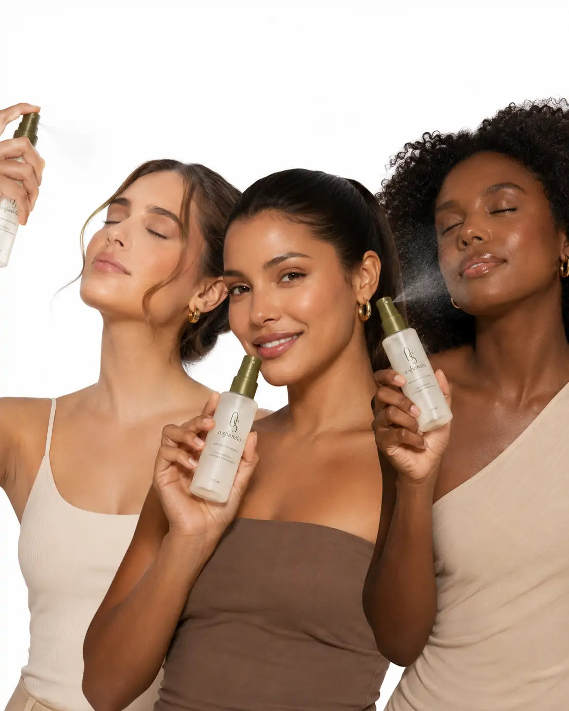 Três mulheres brasileiras de tons de pele diferentes usando a Bruma Fixadora O Sfumato™ em fundo branco